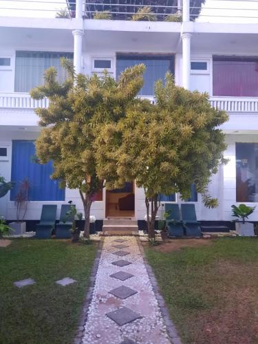 a building with two trees in front of it at White Surfing Beach Resort in Unawatuna
