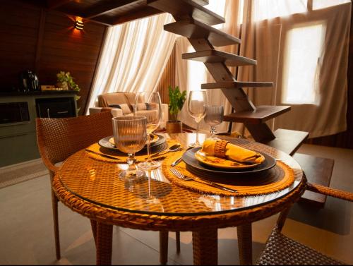 a table with a plate of food and wine glasses at Chalé Maloca in Cariry