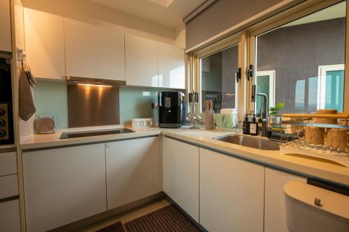 a kitchen with white cabinets and a sink at Afiniti 2BR - Giant Bear Home - Legoland 300m in Nusajaya