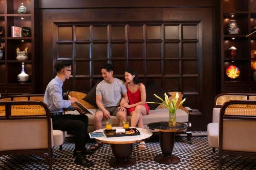 a group of three people sitting on a couch in a room at MAY DE VILLE Crown Hotel in Hanoi