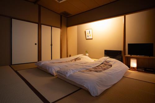 a bedroom with a large white bed in a room at Arima Onsen Takayamaso Hanano in Kobe