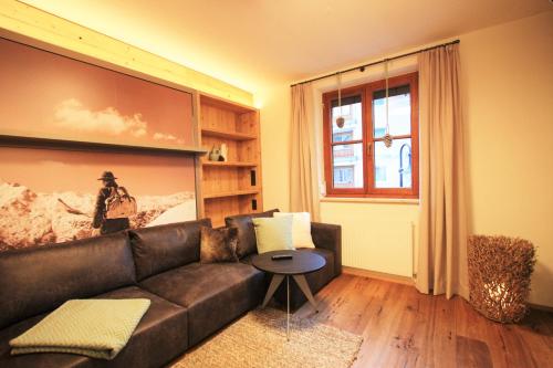 a living room with a leather couch and a table at Dorfplatzl in Ischgl