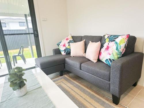 a couch in a living room with pillows on it at Colebee 5 Bedroom near Shopping WiFi Central AC in Schofields