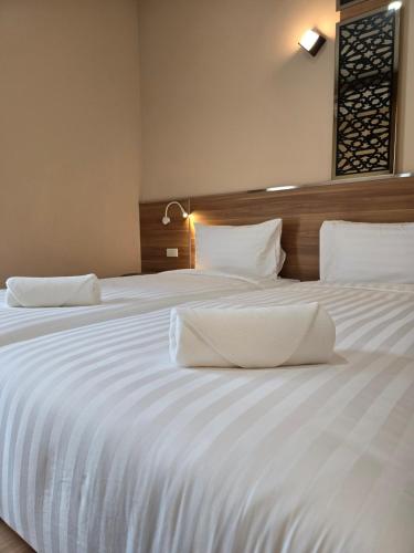 a large white bed with white sheets and pillows at One Budget Hotel Nan Pha Sing โรงแรม วัน บัดเจท น่าน ผาสิงห์ in Nan