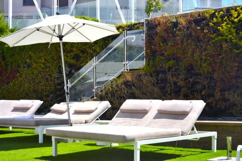 a row of lounge chairs with an umbrella at סי סייד, אילת - סמואל - Sea Side Eilat in Eilat