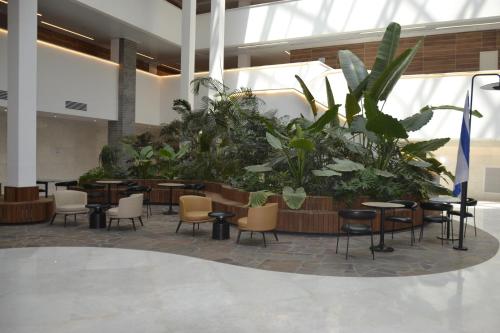 a lobby with tables and chairs and plants at סי סייד, אילת - סמואל - Sea Side Eilat in Eilat