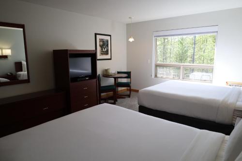 a hotel room with two beds and a television at Glacier Mountain Lodge in Blue River