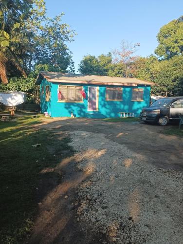 a blue house with a car parked in front of it at Kapeta Cabin in Nuku‘alofa