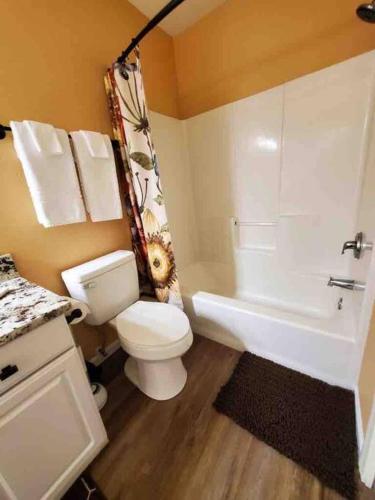 a bathroom with a white toilet and a bath tub at Solar Half-Plex with Chic Style in Country Glen in Keizer