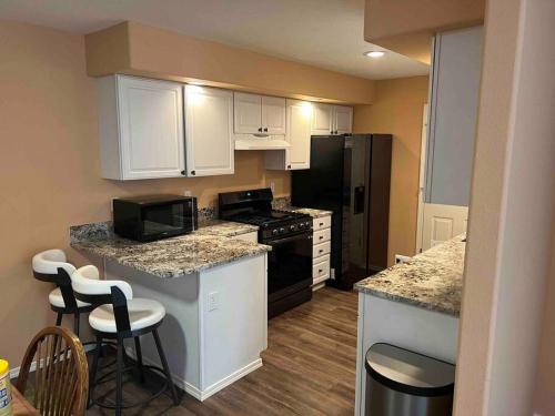 a kitchen with white cabinets and black appliances at Solar Half-Plex with Chic Style in Country Glen in Keizer