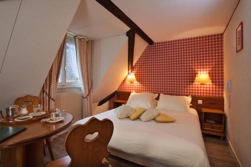 a bedroom with a white bed and a table and a tableablish at Hôtel De La Tour in Ribeauvillé