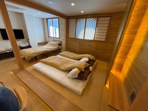 two beds sitting in a room with windows at 日月庵 BnB Sunmoon in Kanazawa