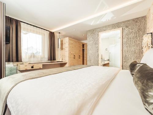 a bedroom with a large white bed and a window at Hotel Bergkristall Zillertal - Adults Only in Hippach