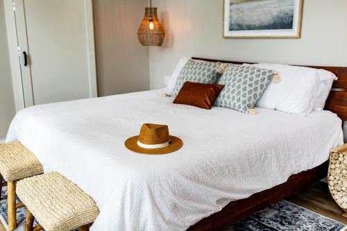 a hat sitting on top of a white bed at The Spruce Villa where luxury meets nature in Panther Creek