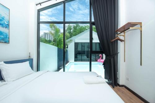 a bedroom with a large window and a swimming pool at Madaguscar Private Pool Villa-Pattaya in Jomtien Beach