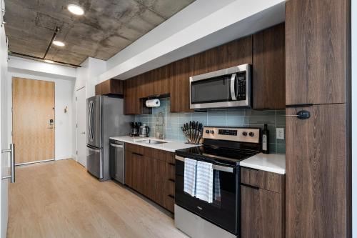 a kitchen with stainless steel appliances and wooden cabinets at 8th fl Amazing views! Lux design! Pool gym Pkg! in Salt Lake City