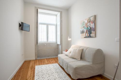 a living room with a white couch and a window at StayINBonfim Porto Suites in Porto