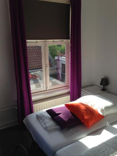 ゼーフェンベルゲンにあるHotel Bij Verhoevenの紫色のカーテンが付いた窓のある部屋のベッド1台分です。