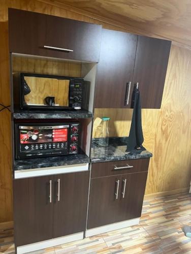 a kitchen with a microwave oven and a cabinet at Cabañas Borde del Sur in El Cardonal