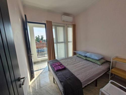 a bedroom with a bed and a large window at Guesthouse Jogja Selatan 2 Yogya South Bantul - Casa of Joy in Bantul
