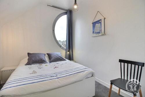 a bedroom with a bed with a window and a chair at Le duplex du linkin in Perros-Guirec
