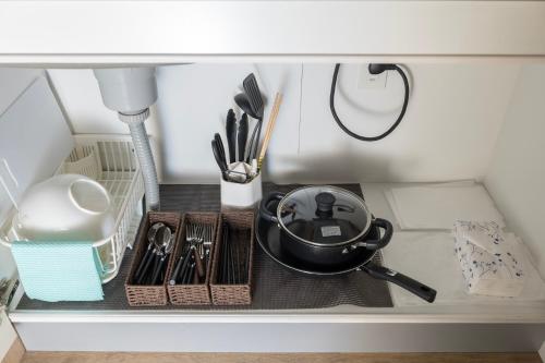 a shelf with a frying pan and other kitchen utensils at e-stay namba in Osaka