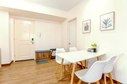 a white dining room with a white table and chairs at Spacious 2BR at SoMa BGC Near SM Aura and Bonifacio High Street in Manila