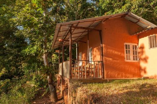 a small orange house with a balcony and trees at Polwaththa Eco Lodges in Digana