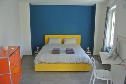 1 dormitorio con cama amarilla y pared azul en A Cà balade in Design, en Miglieglia