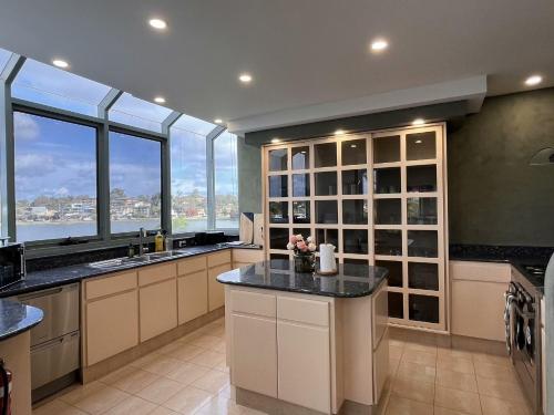 a large kitchen with windows and a large kitchen island at Chiswick Waterfront Retreat in Sydney