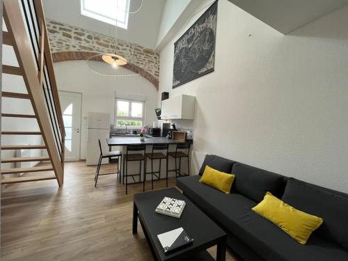 un salon avec un canapé noir et une cuisine dans l'établissement Appartement avec du cachet, à Mont-sous-Vaudrey