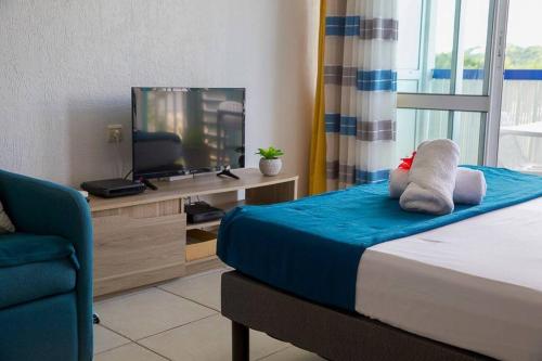a bedroom with a bed with a television and a chair at Le Calypso, Beachside Heaven in Le Gosier