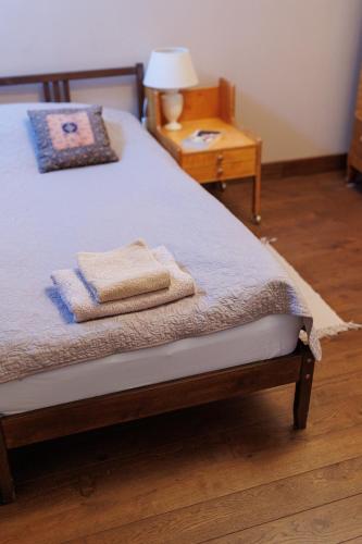 a bed with two towels on it with a night stand at Zamość Dwór Udrycze in Udrycze