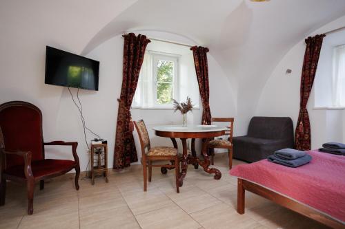 a living room with a table and chairs and a tv at Zamość Dwór Udrycze in Udrycze