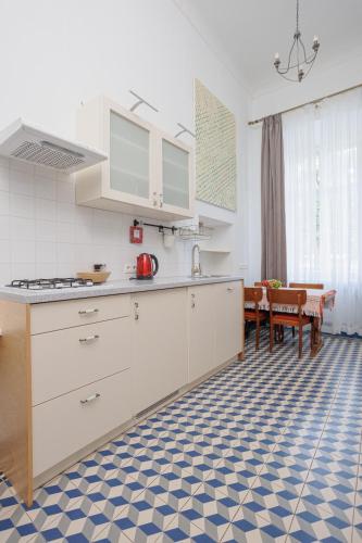 a kitchen with white cabinets and a blue and white floor at Zamość Dwór Udrycze in Udrycze