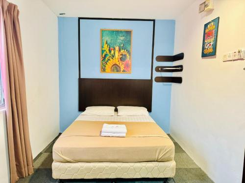 a bed in a room with a painting on the wall at Shangg INN in Ipoh