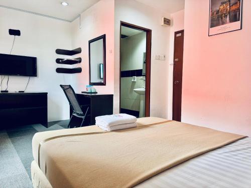 a bedroom with a bed and a tv and a desk at Shangg INN in Ipoh