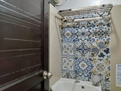 een badkamer met een toilet en een blauwe en witte tegelmuur bij Ann's Guesthouse in Butuan