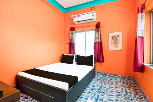 a bedroom with orange walls and a bed in a room at Hotel O by OYO ALO Hotel in Phulbāri