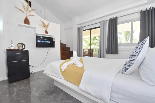 a bedroom with a white bed and a tv at Villa Sunset Boracay in Boracay