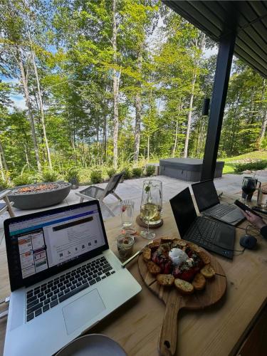 a table with two laptops and a plate of food at Luxury Mountain Retreat with Spa Near Mont Tremblant in La Conception