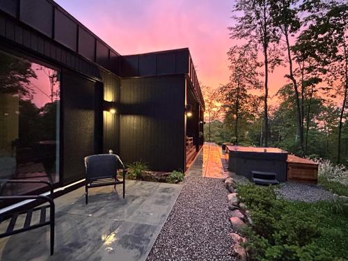 a black house with a patio and a table and chairs at Luxury Mountain Retreat with Spa Near Mont Tremblant in La Conception