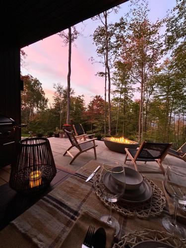 a patio with a table and chairs and a fire pit at Luxury Mountain Retreat with Spa Near Mont Tremblant in La Conception
