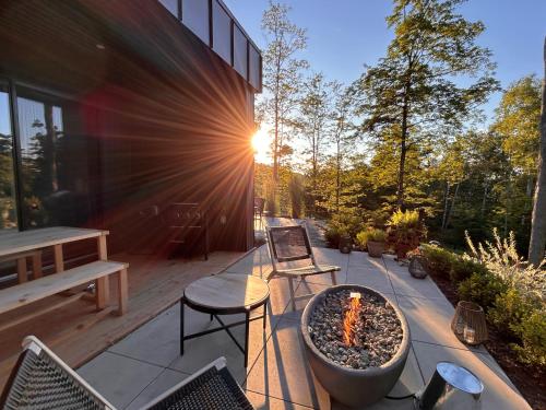a patio with a fire pit and a table and chairs at Luxury Mountain Retreat with Spa Near Mont Tremblant in La Conception