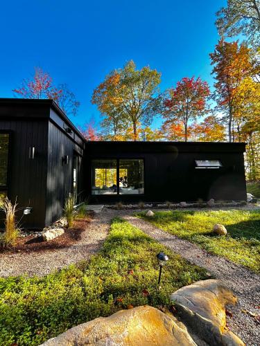 a black house with a black roof at Luxury Mountain Retreat with Spa Near Mont Tremblant in La Conception