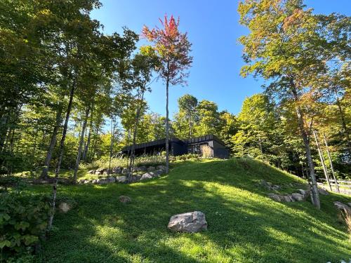 a house on top of a grassy hill with trees at Luxury Mountain Retreat with Spa Near Mont Tremblant in La Conception