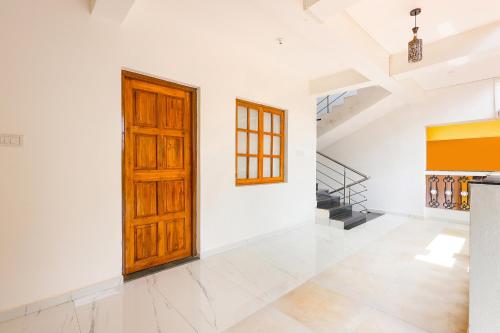 a white room with a wooden door and stairs at Pednekar Plaza Inn in Baga