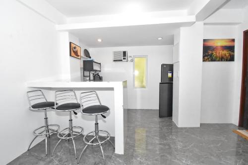 a kitchen with three bar stools and a refrigerator at Villa Sunset Boracay in Boracay
