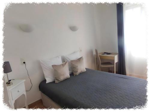 a bedroom with a bed with blue sheets and pillows at Hotel Du Lac in Château-Arnoux-Saint-Auban