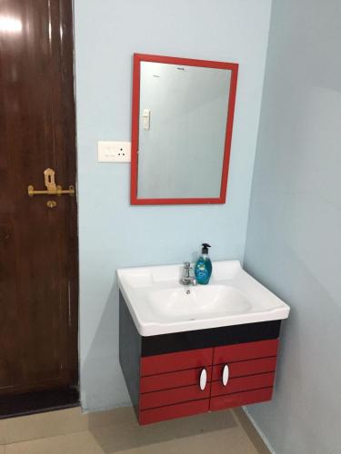 a bathroom with a red and white sink and a mirror at River Heart Homestay in Aranmūla